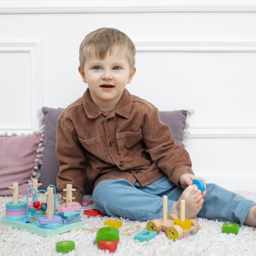 full-shot-smiley-kid-sitting-with-toys (1)